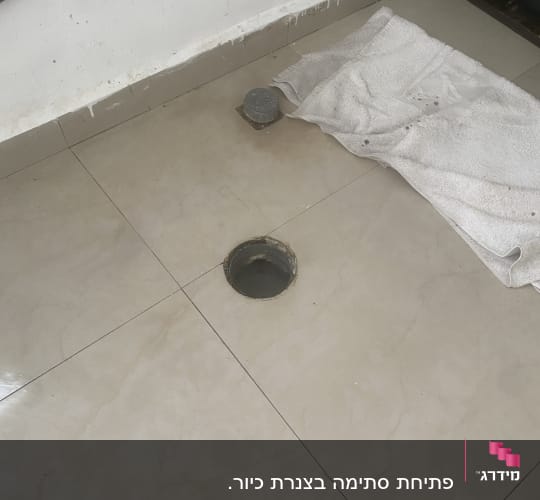 פתח ניקוז ברצפה עם מגבת וכלי עבודה